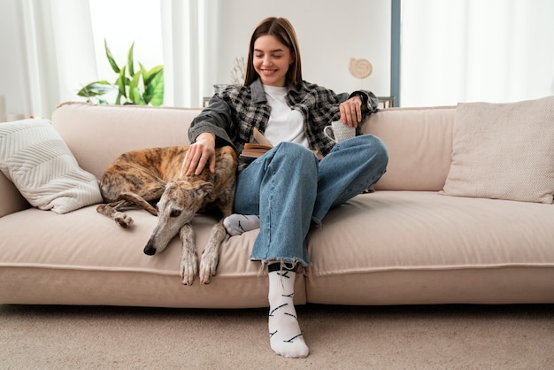 Foto gratuita mujer se sentar, con, perro, en, sofá, vista delantera