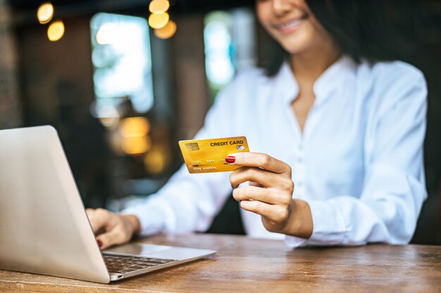 mujer se sentó con una computadora portátil y pagó con una tarjeta de crédito en un café