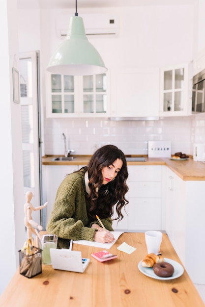 Foto gratuita mujer seria con auriculares dibujar en la cocina