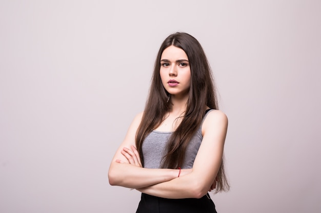 Mujer seria confiada con las manos cruzadas sobre la pared gris.