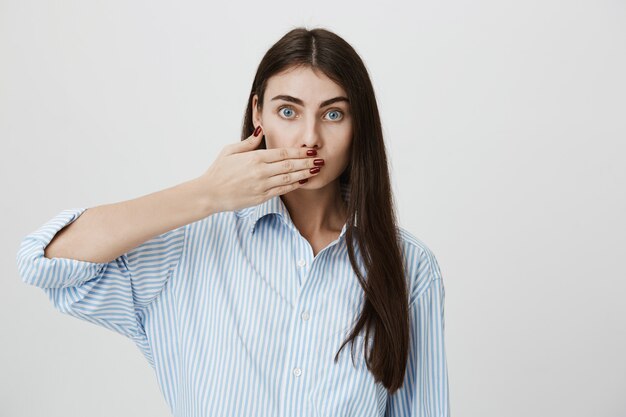 Mujer seria cubre la boca, guarda silencio