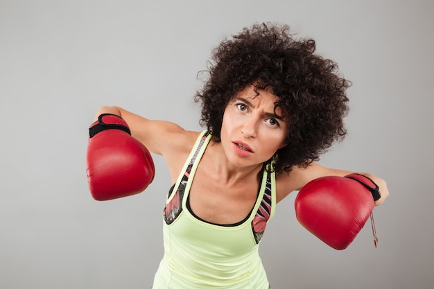 Mujer seria en guantes de boxeo y mirando a la cámara