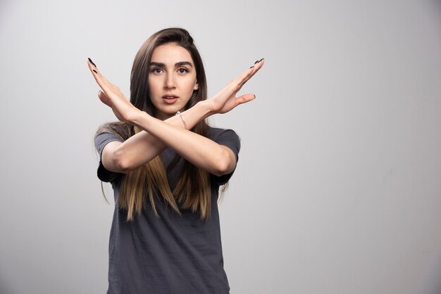 Mujer seria haciendo el signo X con los brazos para dejar de hacer algo.