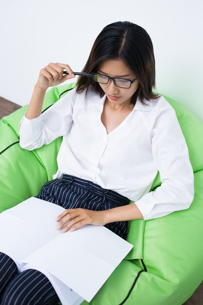 Foto gratuita mujer seria lectura y sentarse en sillas de descargas digitales