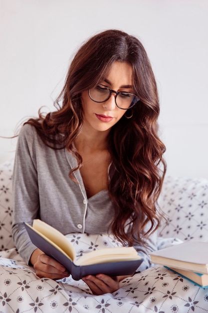 Foto gratuita mujer seria leyendo en la cama