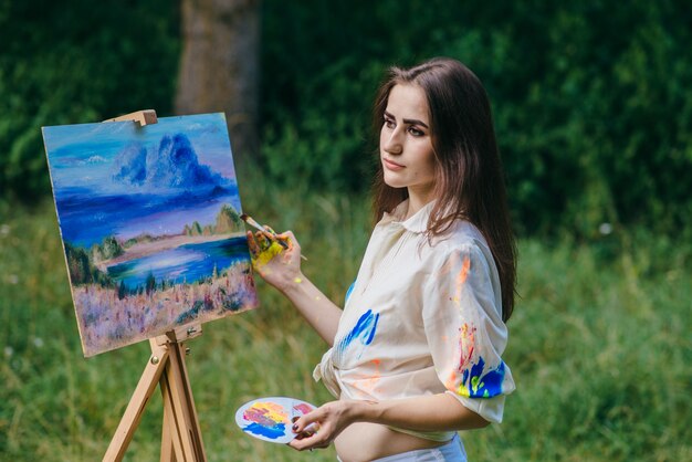 Mujer seria manchada de pintura pintando un cuadro