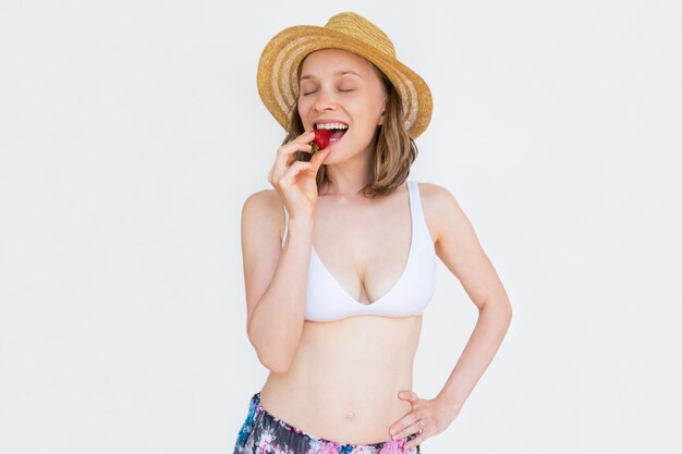 Mujer sexy alegre en ropa de verano comiendo fresa