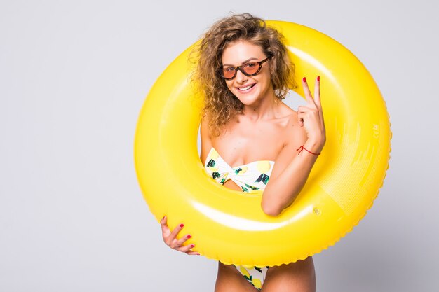 Mujer sexy de cuerpo completo en bikini con anillo inflable amarillo aislado sobre pared blanca