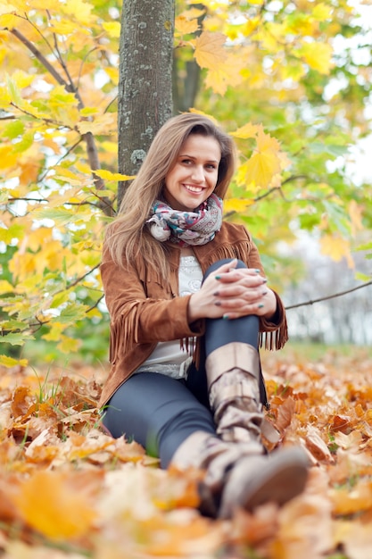 Mujer se sienta en el parque de otoño