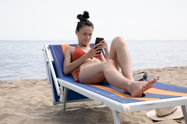 Mujer en silla de playa mirando el teléfono
