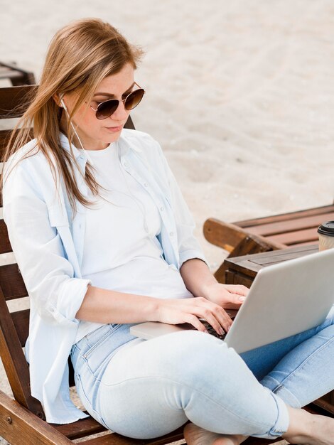 Mujer en silla de playa trabajando en la computadora portátil