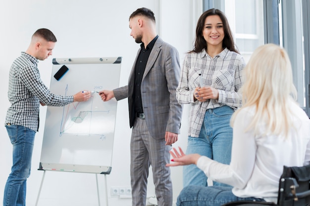 Mujer en silla de ruedas conversando con un colega en el trabajo