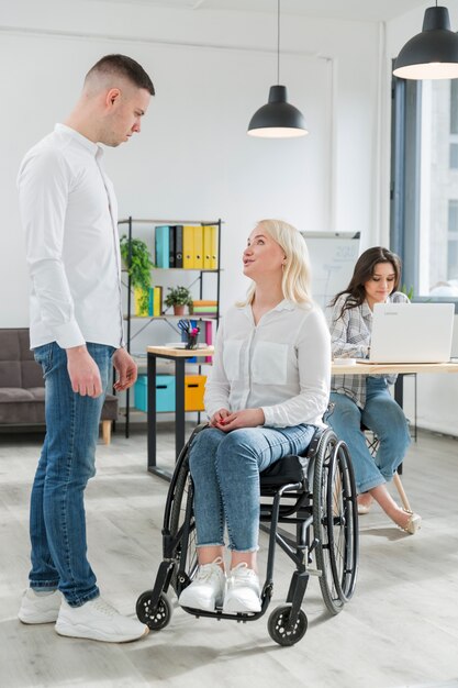 Mujer en silla de ruedas conversando con un compañero de trabajo