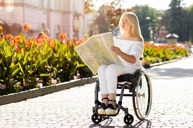 Mujer en silla de ruedas mirando el mapa al aire libre