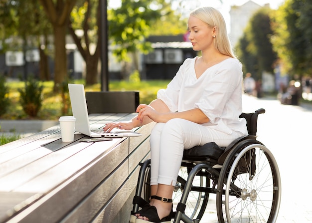 Mujer en silla de ruedas con portátil al aire libre