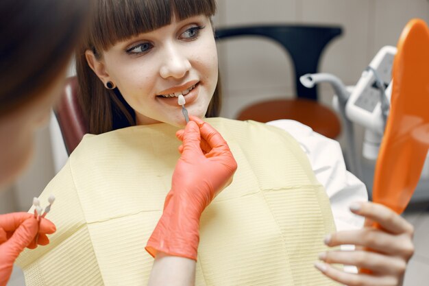 Mujer en un sillón dental. Chica elige un implante. La belleza trata sus dientes