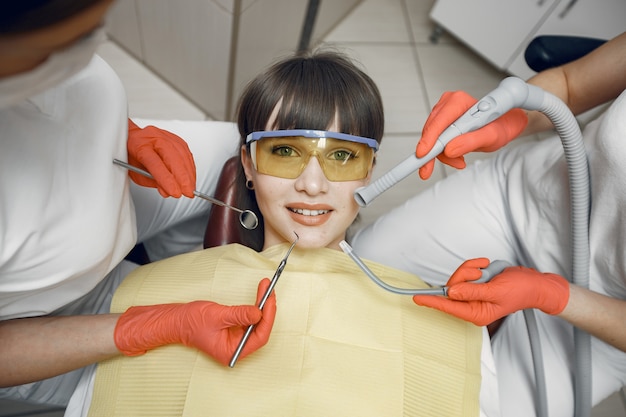 Mujer en un sillón dental. Una niña es examinada por un dentista.Los dentistas tratan los dientes de una niña