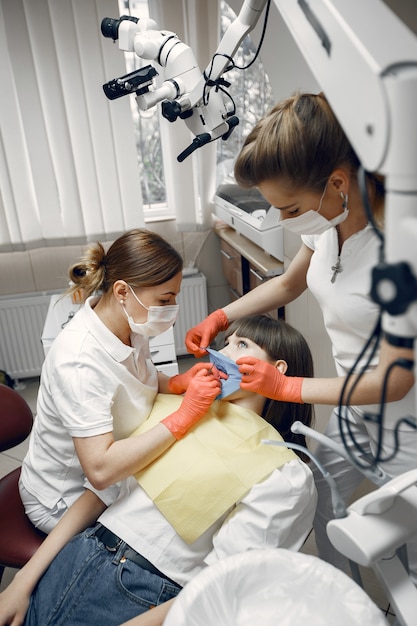 Mujer en un sillón dental. Una niña es examinada por un dentista.Los dentistas tratan los dientes de una niña