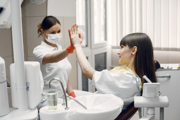 Mujer en un sillón dental. Una niña es examinada por un dentista. El médico da cinco pacientes