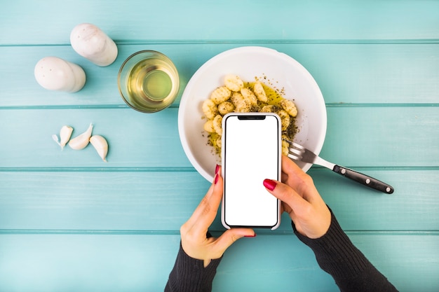 Mujer con smartphone sobre pasta de gnocchi
