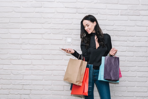 Foto gratuita mujer con smartphone sosteniendo bolsas de colores