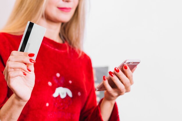 Mujer con smartphone y tarjeta plástica.