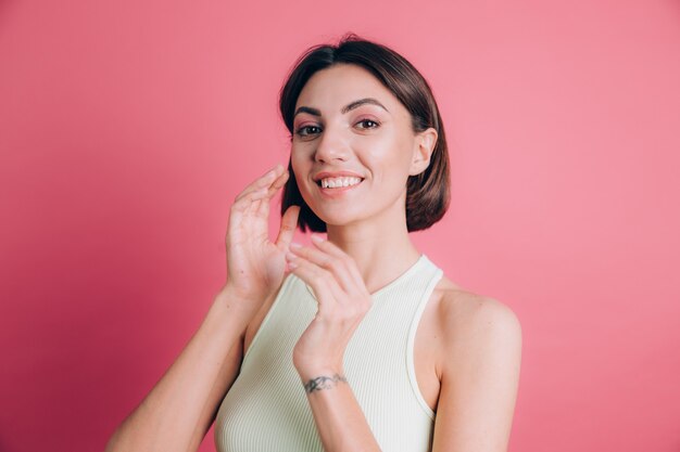 Mujer sobre fondo rosa cara feliz sonriendo mirando a la cámara. Persona positiva.