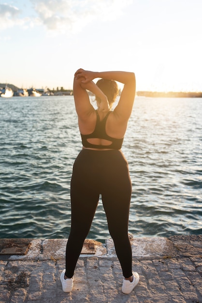 Foto gratuita mujer con sobrepeso haciendo ejercicio al aire libre junto al lago