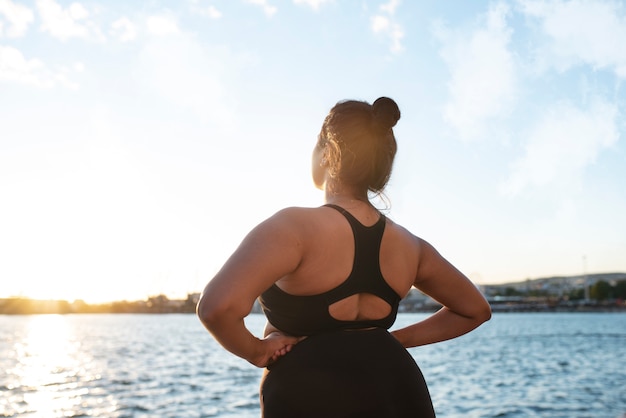 Foto gratuita mujer con sobrepeso haciendo ejercicio al aire libre junto al lago