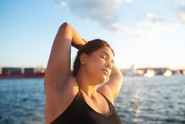 Foto gratuita mujer con sobrepeso haciendo ejercicio al aire libre junto al lago