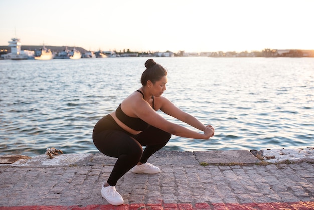 Mujer con sobrepeso haciendo ejercicio al aire libre junto al lago