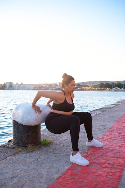 Foto gratuita mujer con sobrepeso haciendo ejercicio al aire libre junto al lago