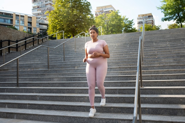 Mujer con sobrepeso haciendo ejercicio en las escaleras al aire libre