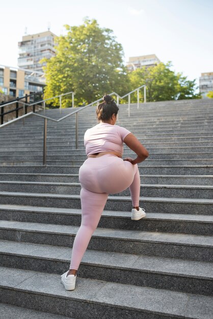 Mujer con sobrepeso haciendo ejercicio en las escaleras al aire libre