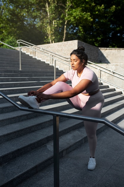 Mujer con sobrepeso haciendo ejercicio en las escaleras al aire libre