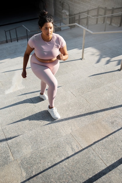 Mujer con sobrepeso haciendo ejercicio en las escaleras al aire libre