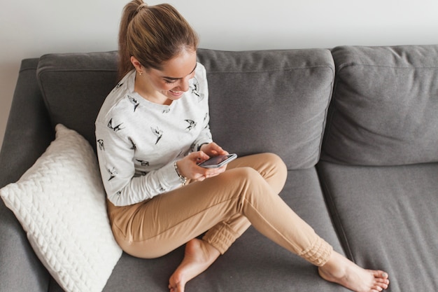 Mujer en sofá con smartphone