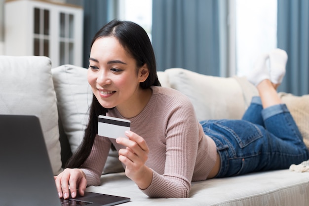 Mujer en el sofá con tarjeta de crédito de compras en línea