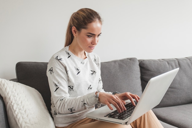 Mujer en sofá trabajando con portátil