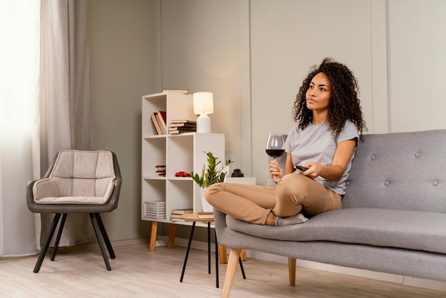 Mujer en el sofá viendo la televisión y bebiendo vino