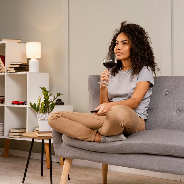 Mujer en el sofá viendo la televisión y bebiendo vino