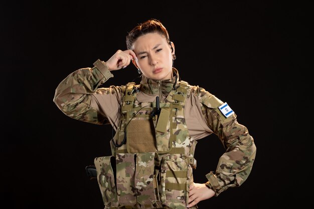 Mujer soldado en camuflaje en la pared negra