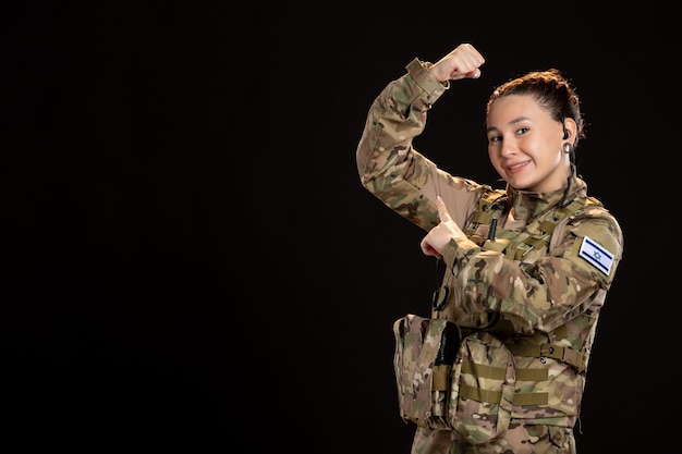 Foto gratuita mujer soldado en camuflaje en la pared negra