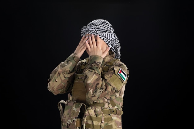 Mujer soldado en uniforme militar sobre pared negra