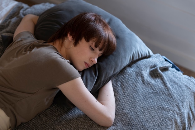 Mujer solitaria joven de tiro medio acostada en la cama