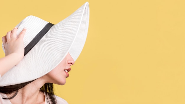 Mujer en sombrero blanco sobre fondo amarillo