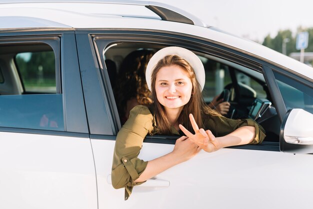 Mujer con sombrero colgando de la ventana del coche