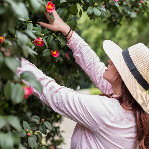 Foto gratuita mujer, en, sombrero, conmovedor, árbol floreciente