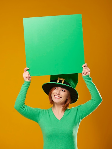 Foto gratuita mujer con sombrero de duende mostrando bandera verde