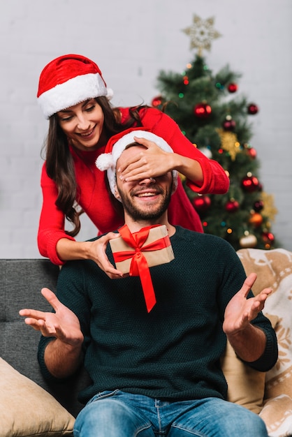 Mujer con sombrero de fiesta cerrando los ojos al hombre feliz.